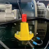 Yellow battery isolator switch beside the starter and alternator of the 40 kW generator
